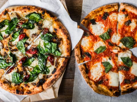 Two Neapolitan-style pizzas with charred, puffy crusts