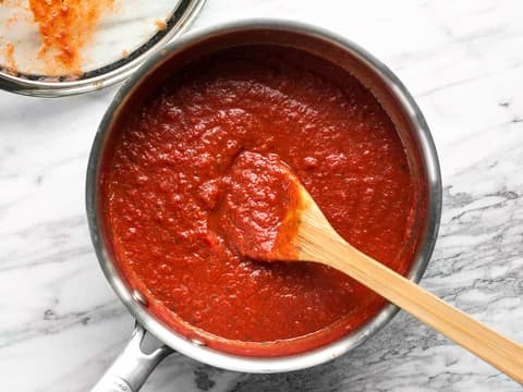 A pot of tomato sauce with a wooden spoon