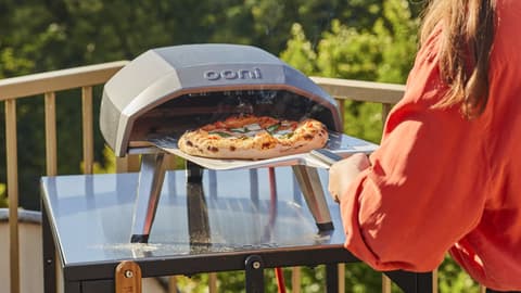 Pizza going into an outdoor pizza oven